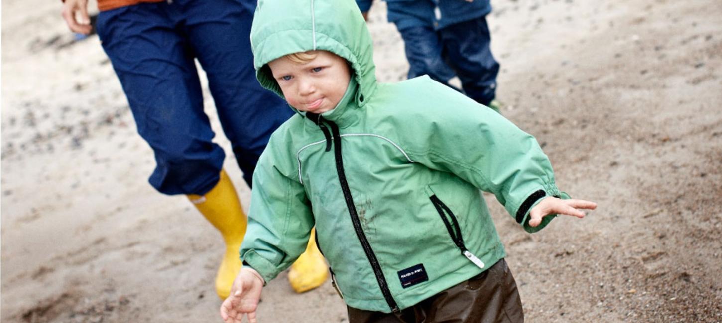 Familie på strand i regntøj